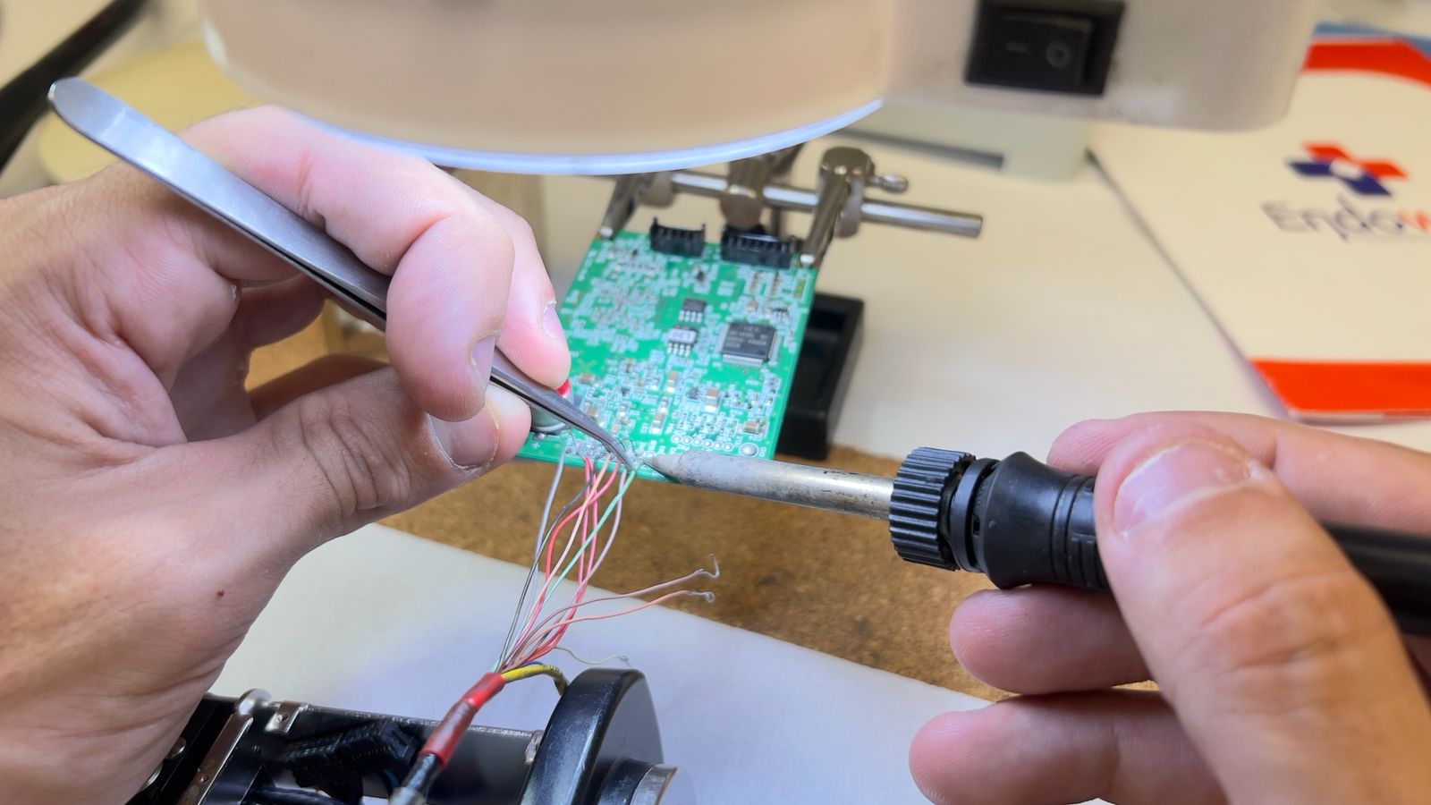 Mãos de um técnico da Endowork a reparar uma placa eletrónica